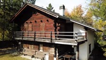 wooden chalet, wooden balcony, red brick, wooden doors, windows, outdoor table and benches, chimney