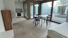 modern interior, white walls, tiled floor, white bed, white table and chairs, wooden cabinet, kitchen area with oven