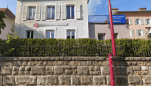 3 story white stucco house, brown roof, white shutters, brick wall, hedges