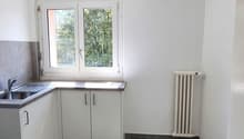 White cabinets, gray tiled floor, window with radiator, stainless steel sink, white ceiling light