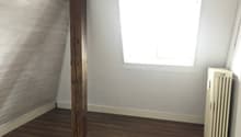 empty room with wooden floor, white walls, wooden beam, window, and a white radiator