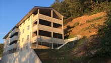 multistory building with basement, concrete facade, multiple balconies, on a slope