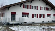 white house, red shutters, sloped roof, covered porch, metal railing, front garden, chimney