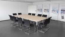 conference room with long table, black chairs, white walls, banners