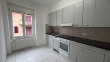 modern kitchen with white tiles, white cabinets, black countertops, white appliances, window with view to the outside