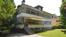 2 story house, beige exterior, brown roof, balcony, stairs, garden, lawn, chimney, multiple windows