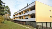 3 story apartment building, yellow and white, balconies, garage