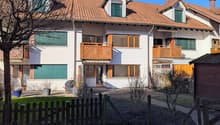 3 story apartment building, brown roof, white walls, wooden balconies, small garden, wooden fence