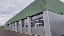 Warehouse, large garage doors, large windows, green and grey exterior, multiple entrances