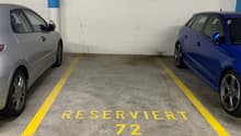 an underground parking garage with a gray and blue car parked in parking spot number 72, along with a blue car parked in parking spot number 73