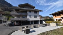 3 story building, grey, underground garage, multiple balconies, mountain view, car in the driveway