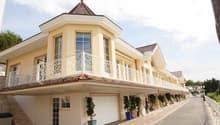 2 story house, yellow exterior, multiple windows, balcony, garage, paved road