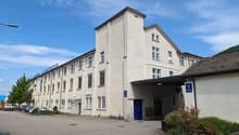3-story office building, beige exterior, multiple windows, blue door, parking lot in front, green vegetation, street light
