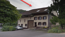 2 story house, brown roof, white windows, brown door, car parked in front