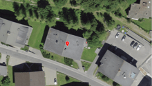 Aerial view of a neighborhood with several houses and a road, marked with a red pin.