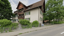 3 story house, brown roof, green shutters, balconies, garden, fence