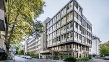 modern, gray, large office building with many windows and raised ground floor