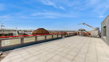 Large open rooftop terrace with tiled flooring, glass railings, and views of the surrounding cityscape. The terrace features a domed structure and other architectural elements.