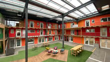 modern building with multiple levels, wooden floors, green turf, communal seating area