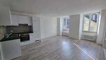 empty kitchen with white cupboards, black countertop, modern appliances, windows with a view