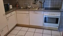white tiled floor, white cabinets, black tiled wall, white sink, dishwasher, microwave, oven, countertop, silver appliances