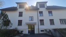 white 2 story building, multiple windows, sloped roof, paved entrance