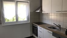 white cabinets, white countertop, stainless steel sink, oven and stove, range hood, tiled wall, window with curtain