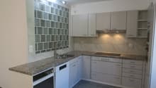 modern kitchen with granite countertops, stainless steel sink, dishwasher, electric stove, cabinets, power outlets, and a power switch