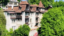 a 3 story building, white painted exterior, brown roof, balconies