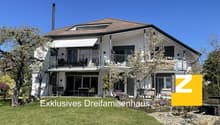 2 story house, white exterior, brown roof, large windows, balcony, garden, trees