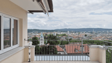 balcony with large windows, black metal railing, tiled floor, city view