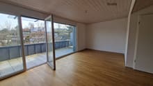 Empty studio with wooden floor, glass sliding doors, balcony, and wooden ceiling.