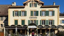 Hotel with a restaurant and tea room, red-brick facade, green shutters, a person in front of the entrance