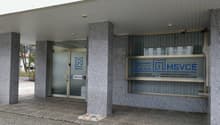 Office building, glass entrance, gray facade, security cameras, signage