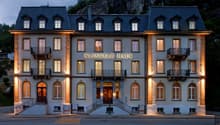 A multi-story hotel building with a traditional European architectural style, featuring stone walls, balconies, and large windows. The building is illuminated at night, creating a warm and inviting atmosphere. The name 'Klingele Haus' is prominently displ