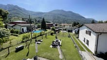 Complex of houses with swimming pool, garden area, and open view of the mountain.