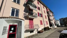 multi-family apartment building, balconies, red doors, mailbox area, fenced in front