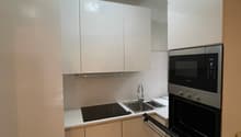 Modern kitchen with white cabinets, tile flooring, microwave, sink, gas stove, and oven