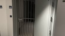 Entrance with metal gate, small hallway, tiled floor, and metal ceiling fixtures.