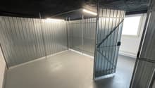 Empty room with metal walls, concrete floor, and two metal doors.