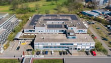 Industrial building, rooftop solar panels, multiple floors, large parking lot