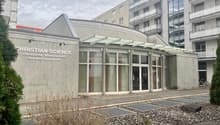 Building exterior of Christian Science with entrance, concrete wall, glass windows, glass doors, and bicycle parked outside.