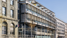 Gray building, large windows, metal railings, balcony, glass entrance, street lamp
