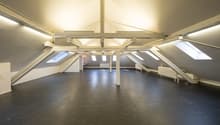 Empty attic room, wooden beams, skylights, radiators, white walls, black floor