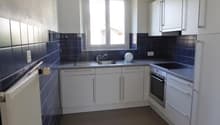 U-shaped kitchen with white cabinets, blue tile backsplash, and stainless steel appliances including a dishwasher.