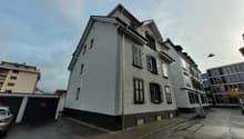 3 story building, gray exterior, multiple windows, two garages