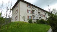 4 story apartment building, red shutters, white walls, located on a slope