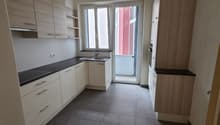 empty kitchen with tiles floor, white cabinets, black countertops, and stainless steel sink and faucet