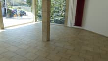 large empty room with large windows, tiled floor, large pillar, white walls