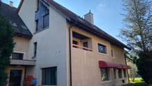 2 story house, beige exterior, brown roof, red awnings, balcony, windows, chimney